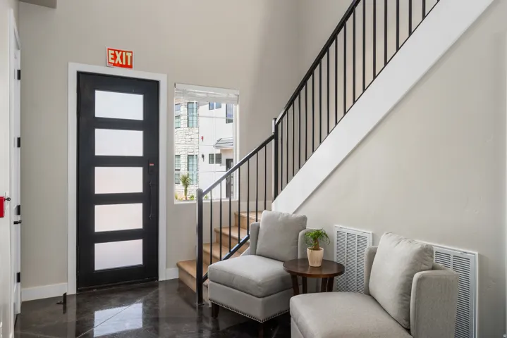 Entryway featuring a black door with frosted glass panels, dark polished flooring, and a modern staircase with black wrought iron spindles and wood treads