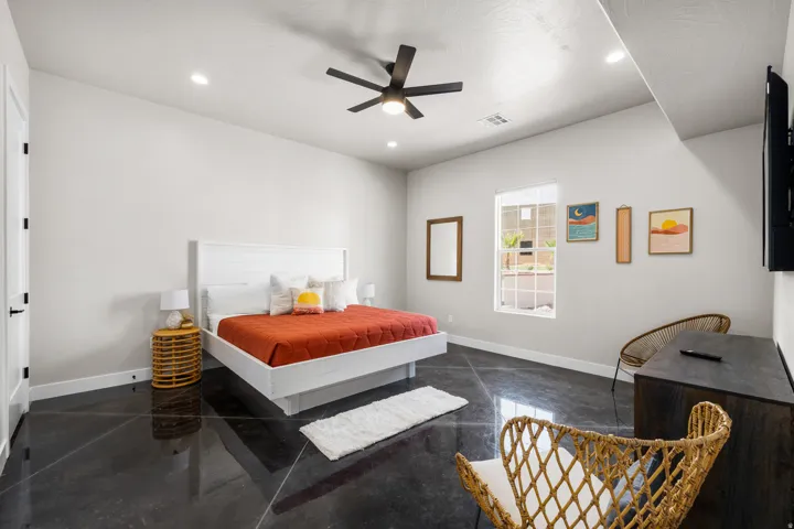 Spacious room featuring polished concrete flooring, recessed lighting, a ceiling fan, a window with exterior views, and a solid core door