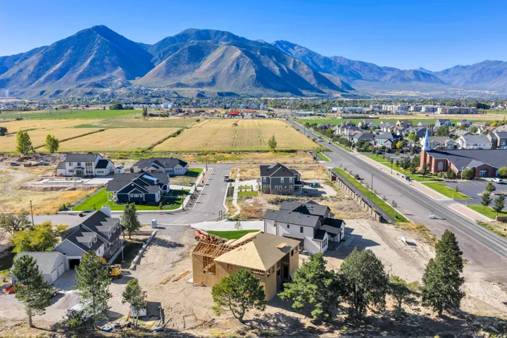 Mountain backdrop with expansive agricultural fields, a developing residential community, and established infrastructure
