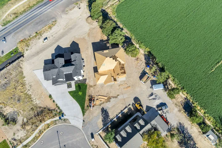Newly constructed residence featuring a multi-gabled dark gray roof, a paved driveway, and a manicured lawn area