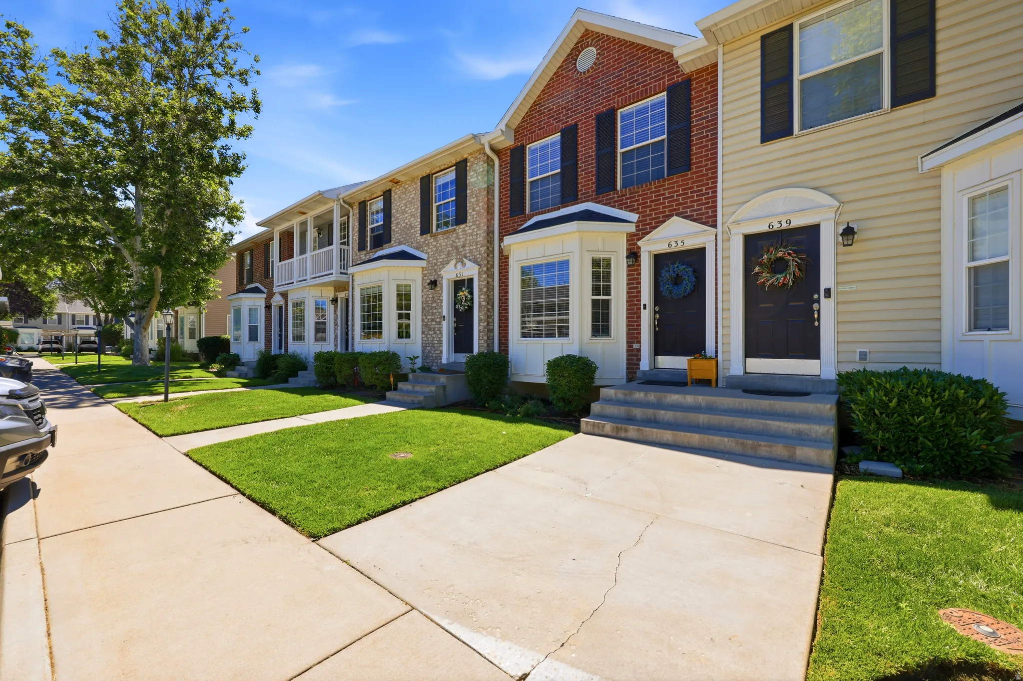 Brick and siding exterior featuring dark shutters, bay windows, and covered entryways