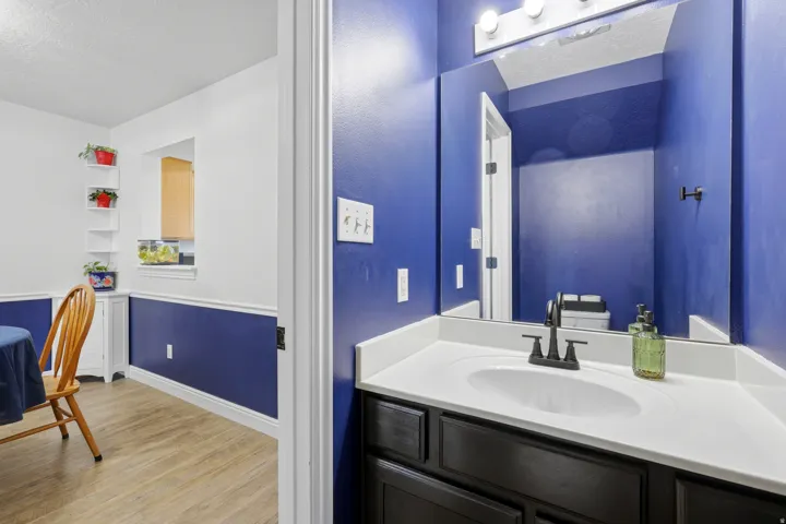 Bathroom vanity featuring a white countertop with integrated sink, matte black faucet, and a large wall-mounted mirror