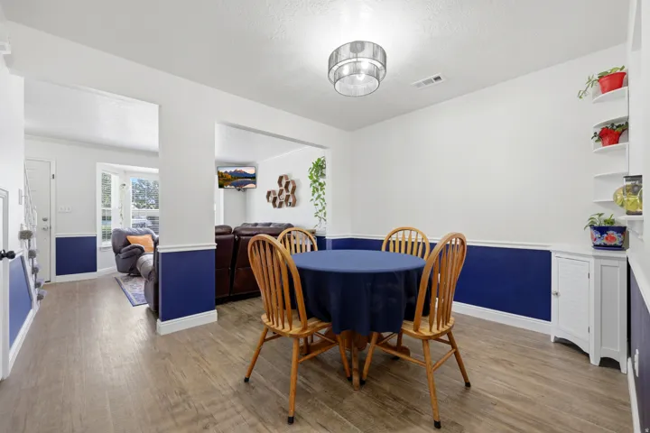 Open-concept living area with wood-finish flooring, two-tone wall paint, a bay window, and a built-in corner cabinet with shelving
