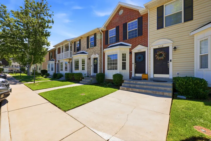 Brick and siding exterior featuring dark shutters, bay windows, and covered entryways