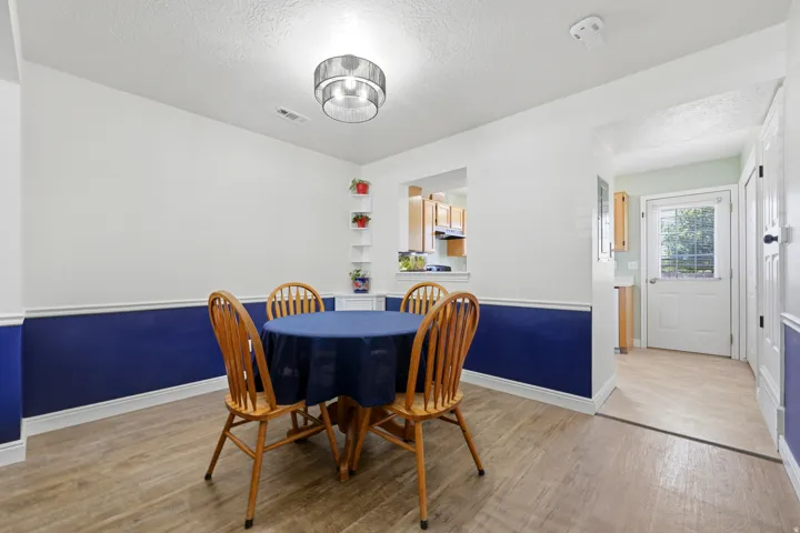 Dining area featuring wood-finish flooring, two-tone wall treatment with wainscoting, and a contemporary ceiling light fixture