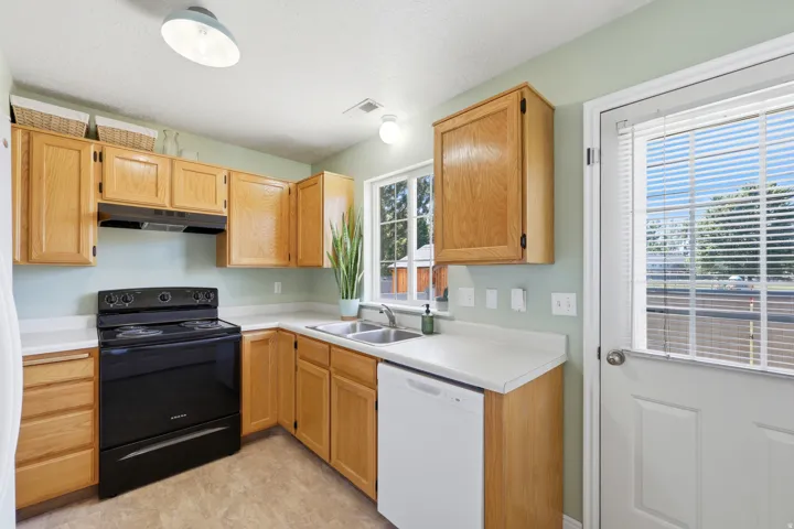 Kitchen featuring light wood cabinetry, white countertops, a double basin sink, and wood-finish flooring
