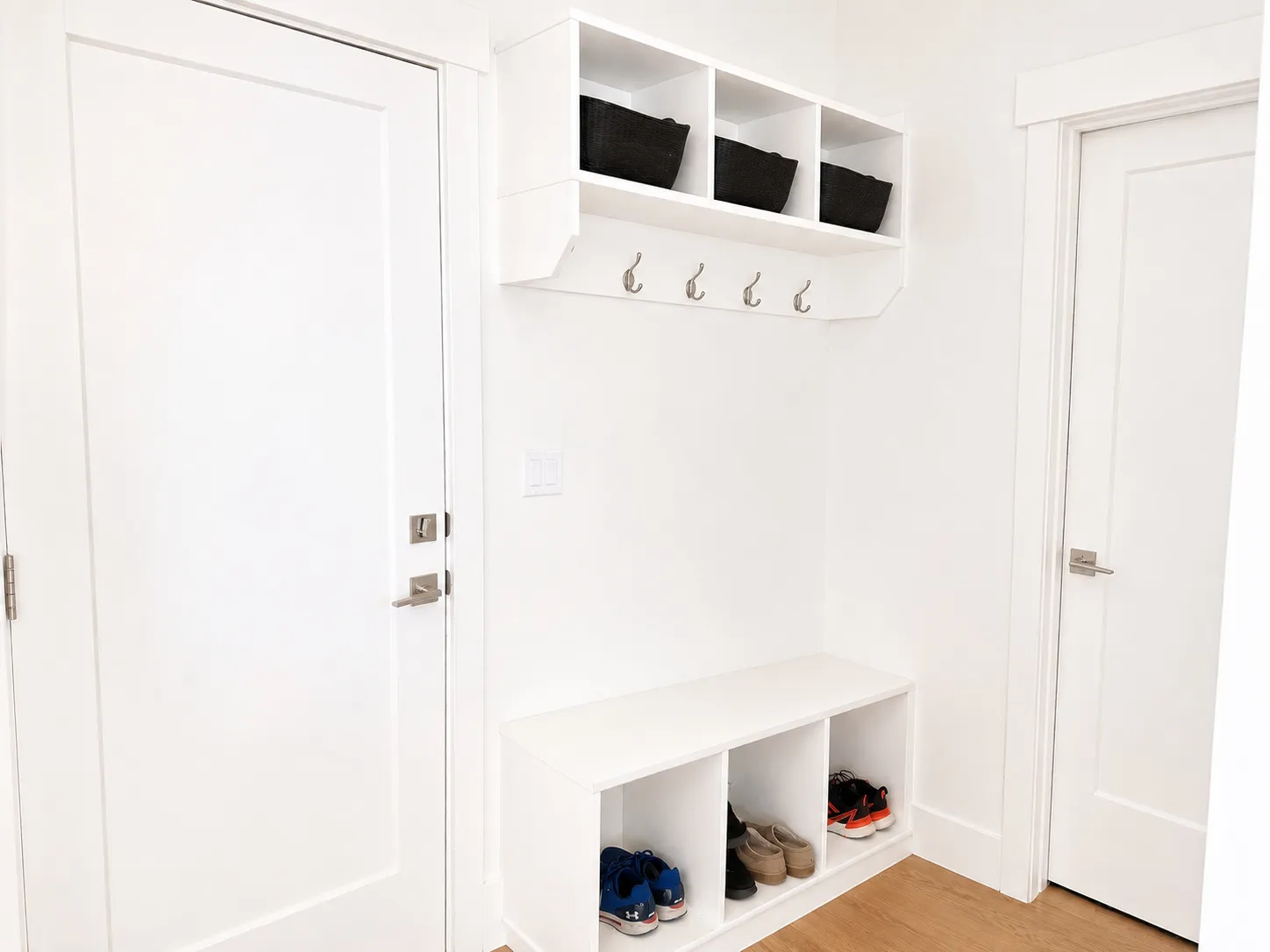 Custom built-in mudroom storage featuring a bench with integrated cubbies, upper shelving units, and coat hooks