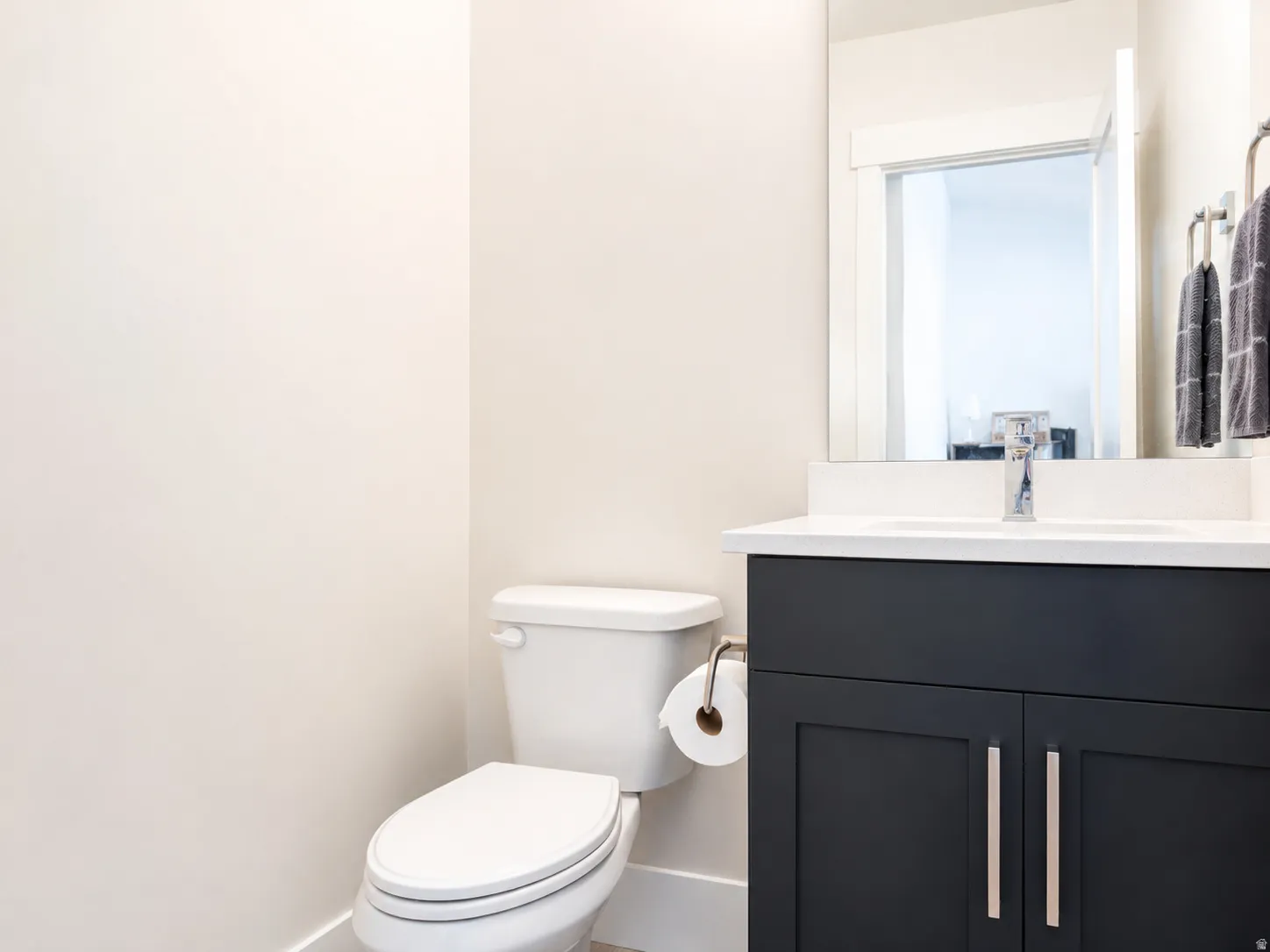 Bathroom featuring a dark wood-finish vanity with a white countertop and integrated sink, chrome faucet, and rectangular mirror