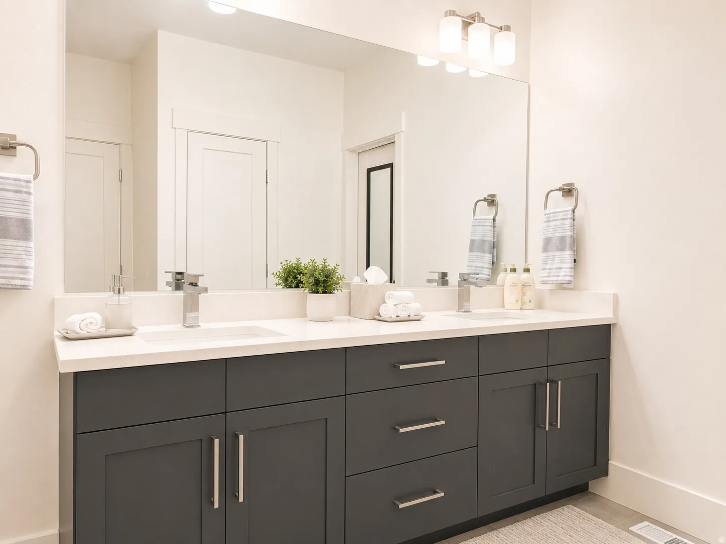 Dual vanity featuring dark gray cabinetry, white countertops, undermount sinks, and brushed nickel fixtures