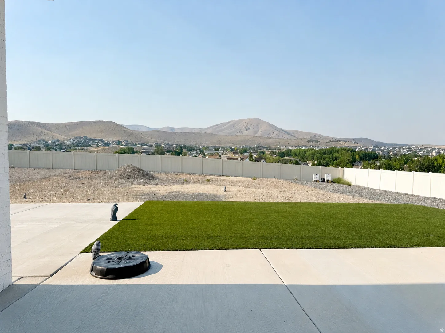 Expansive concrete patio with a rectangular artificial turf lawn