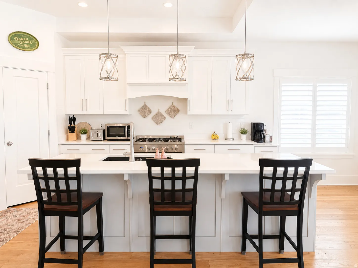 Bright kitchen featuring a substantial island with seating, white cabinetry, and wood-finish flooring