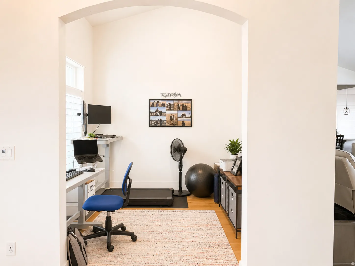 Arched doorway leading to a versatile room with light wood-finish flooring, white walls, and a recessed window