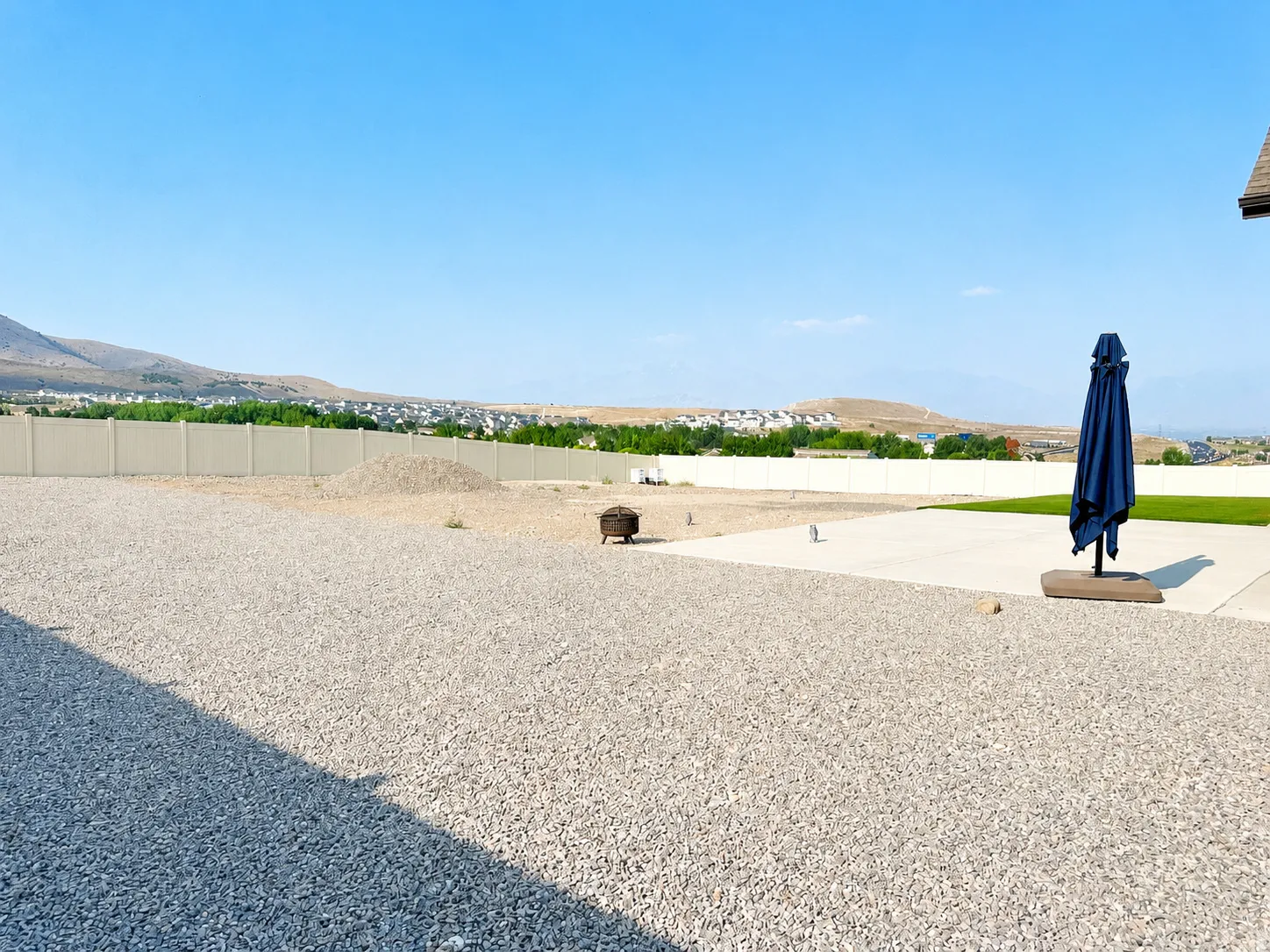Expansive outdoor space featuring a gravel-covered area, a concrete patio, and a section of artificial turf