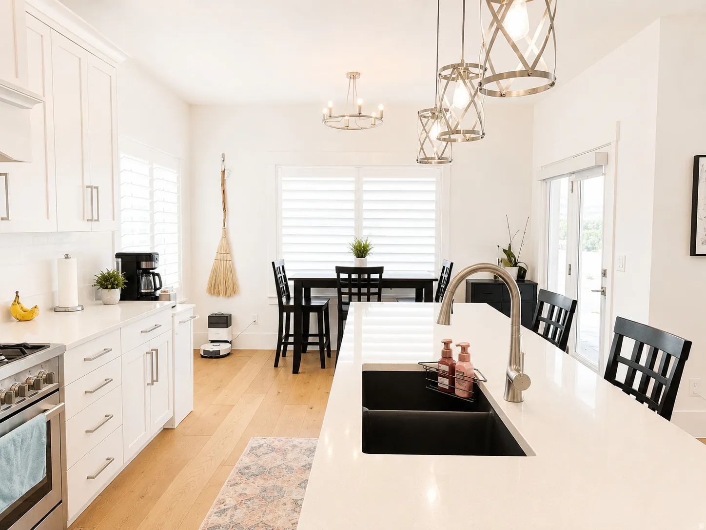 Spacious kitchen featuring white cabinetry, light wood-finish flooring, and a large central island with an integrated double sink