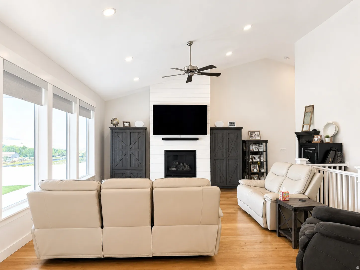 Living area featuring a floor-to-ceiling fireplace with shiplap surround, vaulted ceilings, recessed lighting, and wood-finish flooring