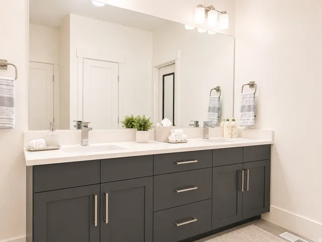 Dual vanity featuring dark gray cabinetry, white countertops, undermount sinks, and brushed nickel fixtures