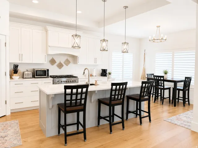 Open-concept kitchen featuring an expansive island with seating, stainless steel gas range, white cabinetry, and wood-finish flooring