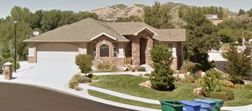 Ranch-style residence featuring a stone and stucco facade, an integrated two-car garage, and a curved concrete driveway