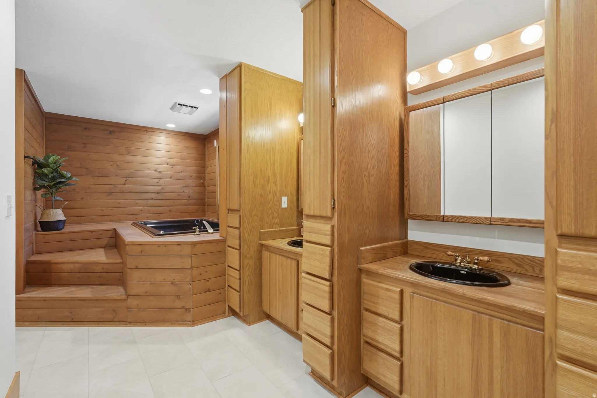 Primary bathroom with wood-paneled bathroom featuring a built-in jetted tub, stepped platform, and white tile flooring