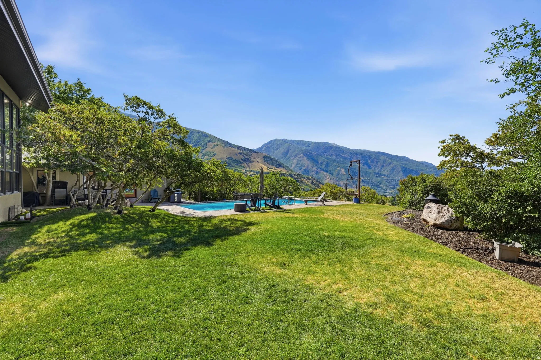 Expansive lawn with mature trees and a swimming pool, complemented by distant mountain scenery