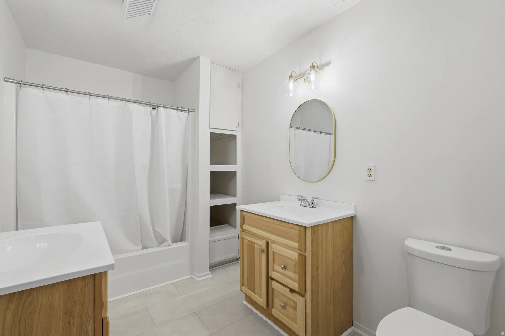 Bathroom featuring dual wood-finish vanities with white countertops and integrated sinks