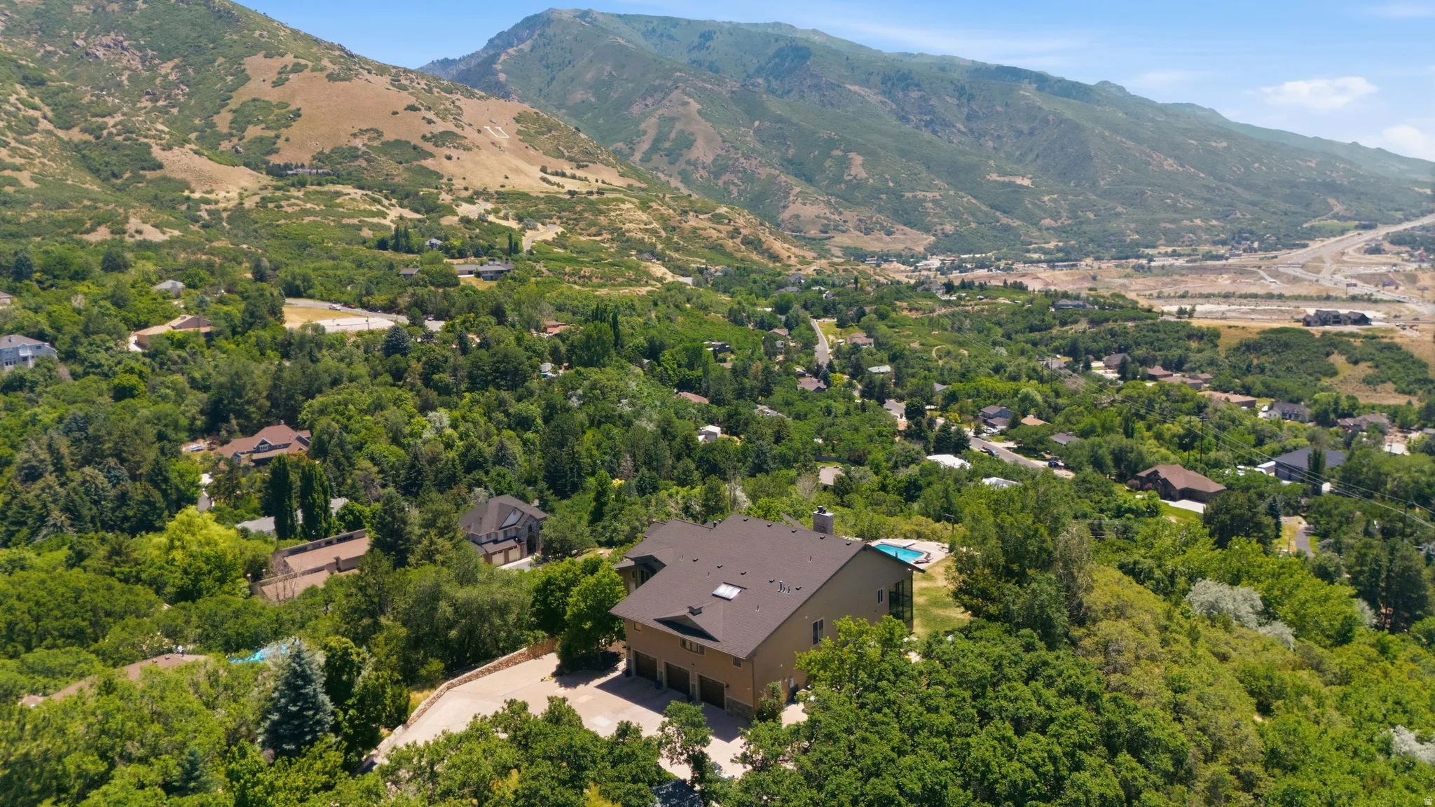 Expansive property featuring a multi-story residence with a brown roof and multiple skylights