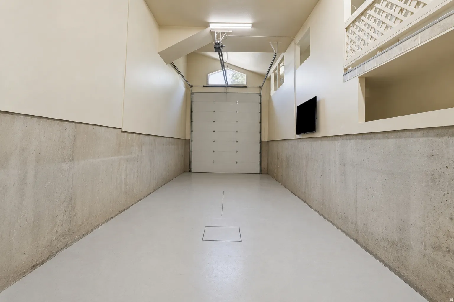 Spacious RV garage featuring a light gray epoxy floor and concrete lower walls
