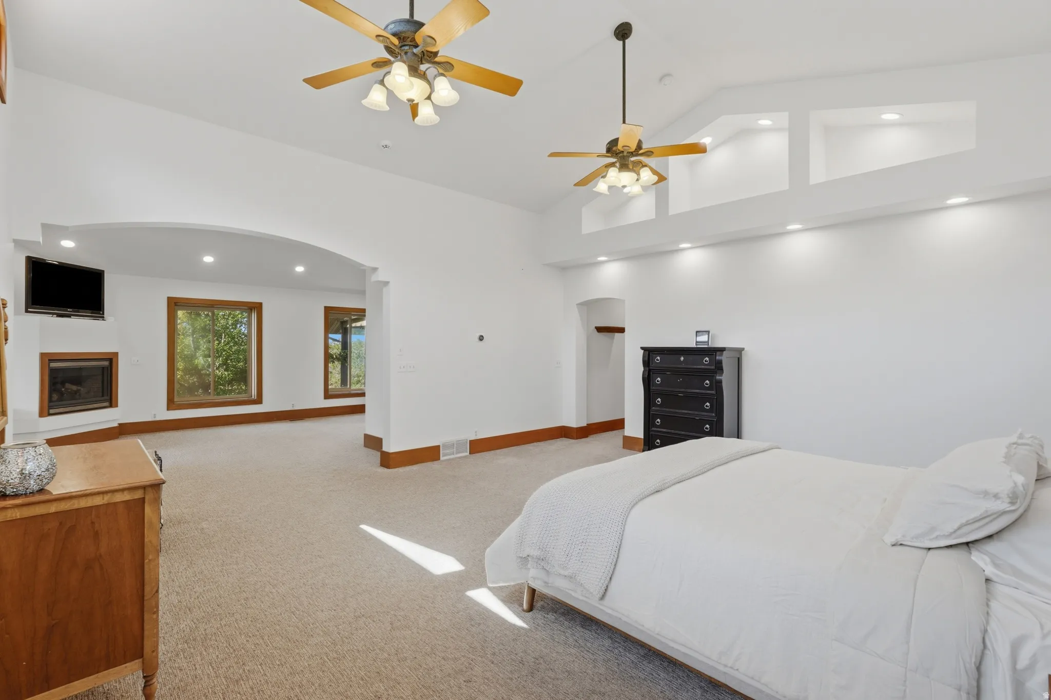 Spacious room featuring vaulted ceilings, recessed lighting, and two ceiling fans