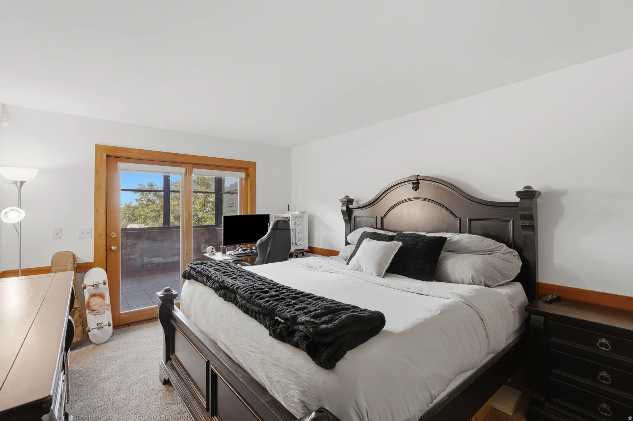 Bedroom featuring carpet flooring, white walls, and a sliding glass door with wood trim opening to the sunroom