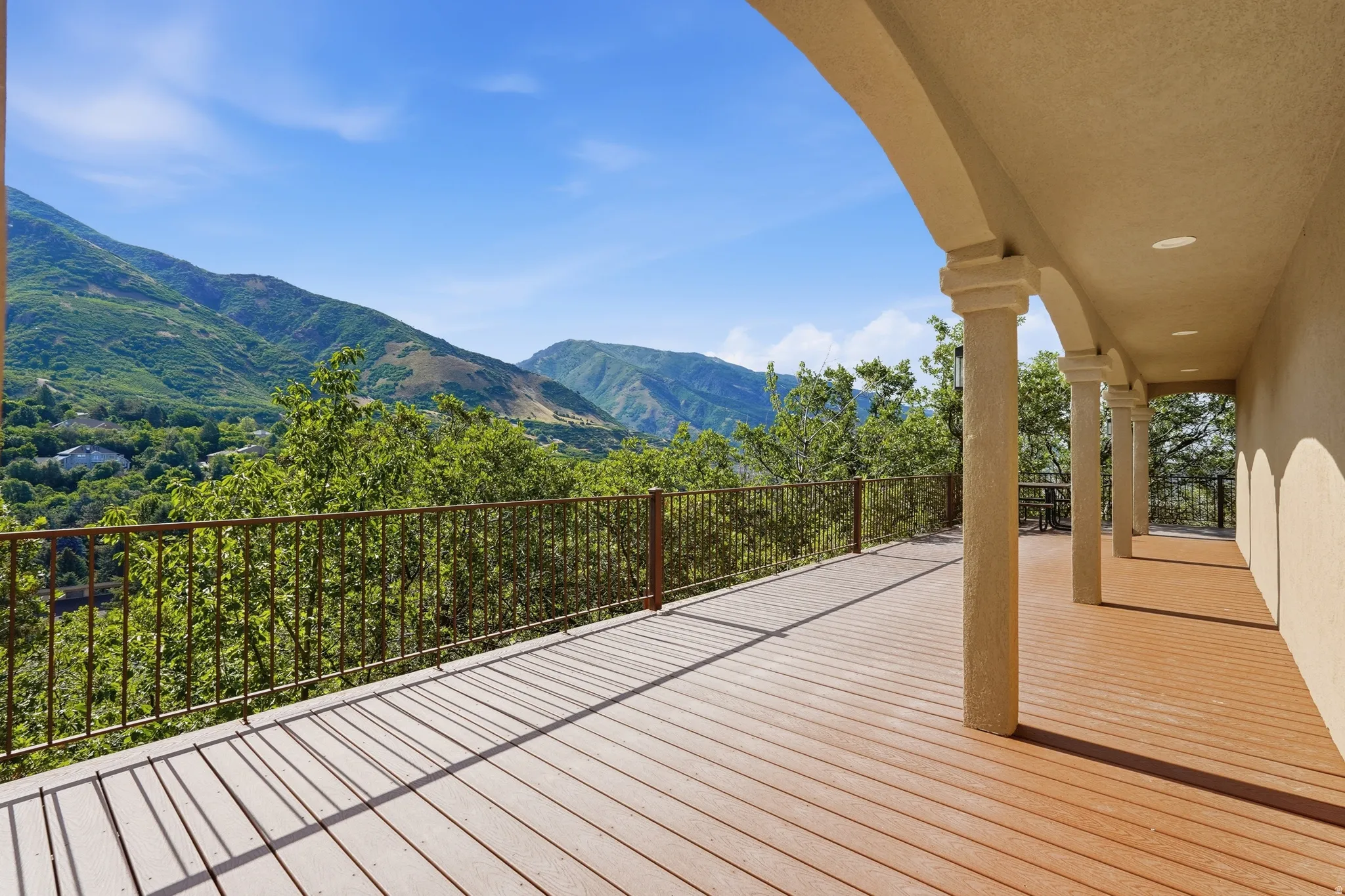 Expansive covered patio featuring a wood-finish floor, arched columns, and recessed lighting