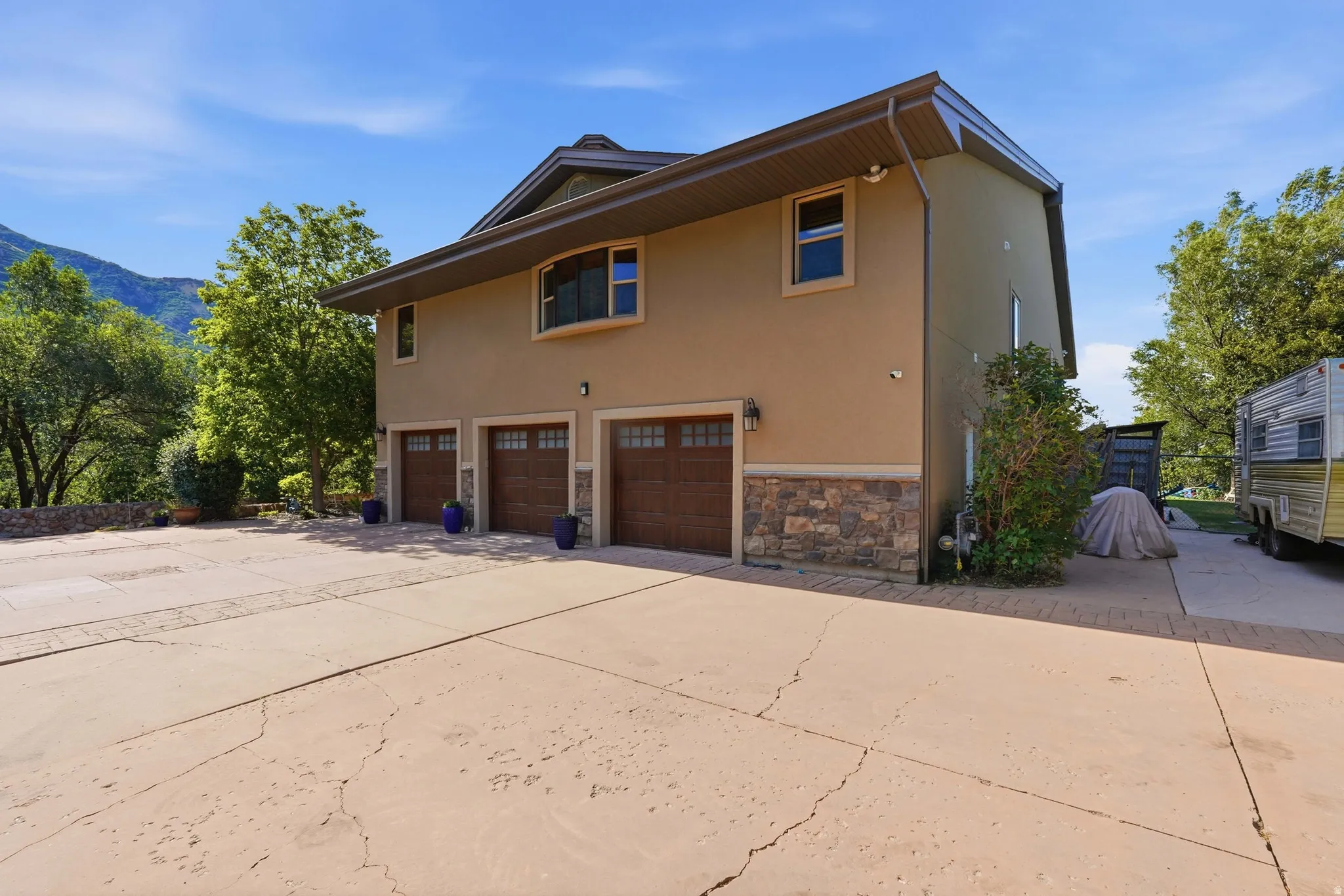 Stucco exterior featuring a stone accent foundation and three individual garage doors