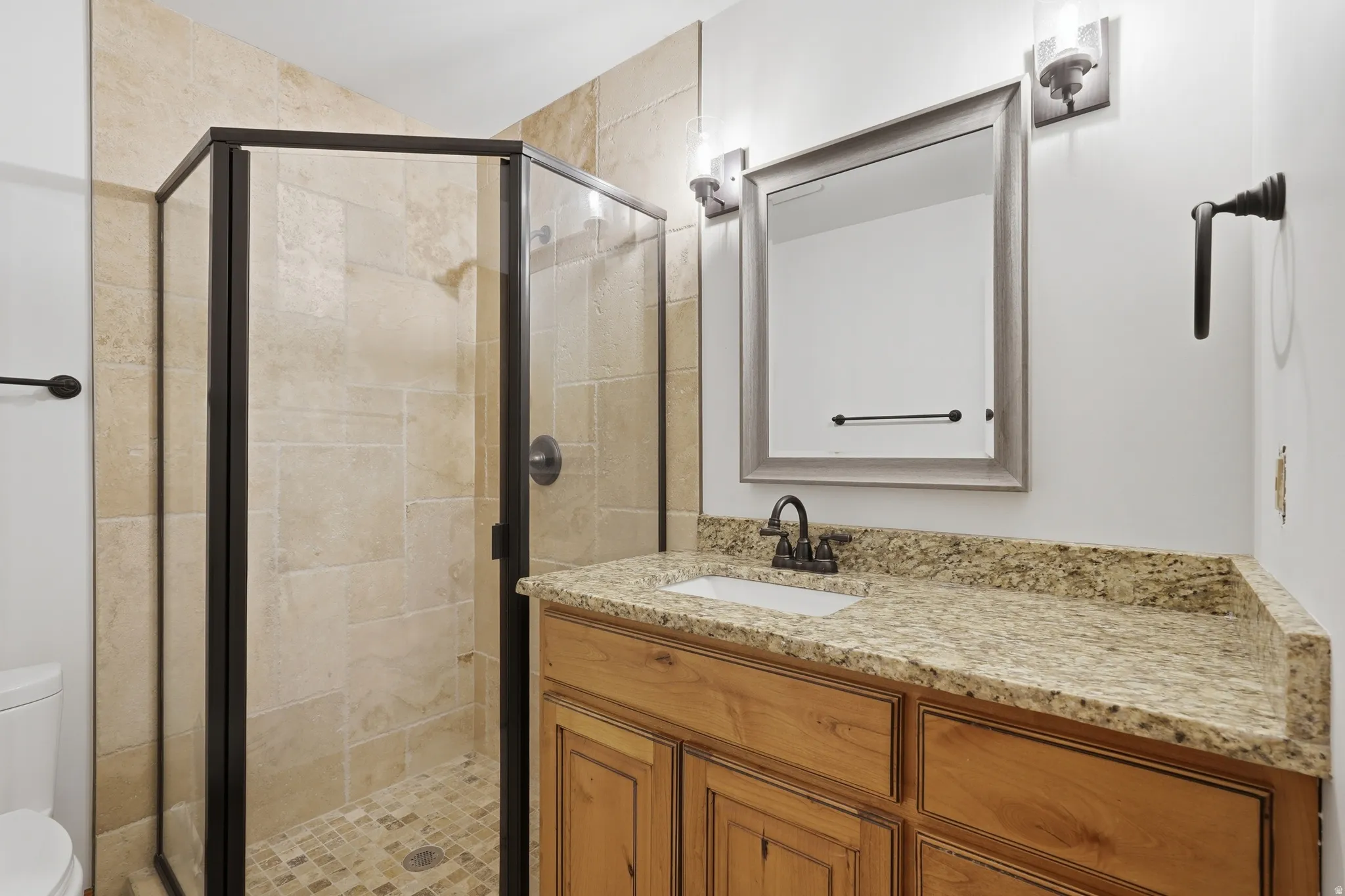 Bathroom featuring a standing shower with a glass enclosure, light-toned tile walls, and a mosaic tile floor