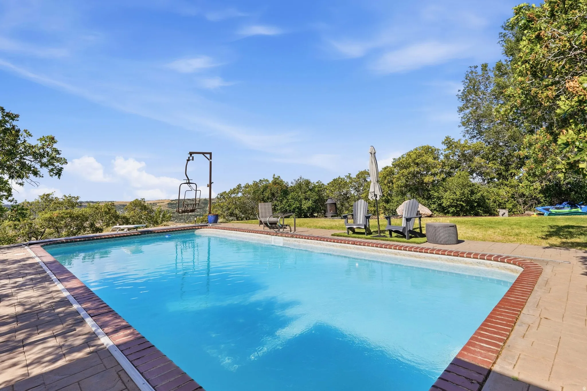 In-ground swimming pool with a brick coping and paver surround overlooking the valley