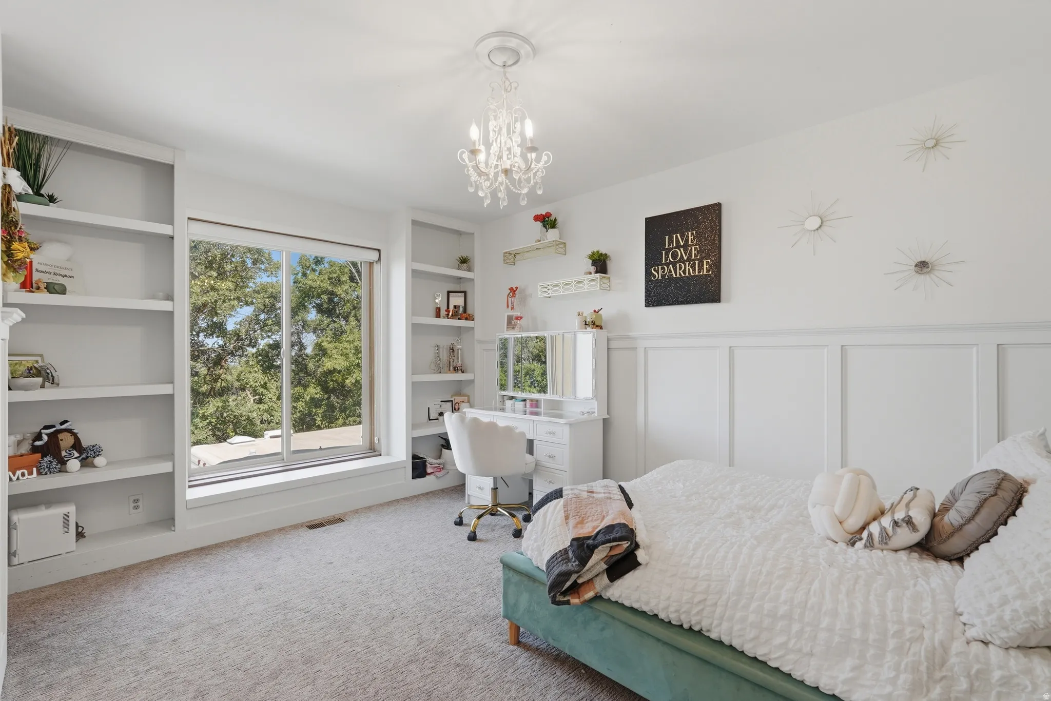 Spacious room featuring a large window, built-in shelving, wainscoting, and a decorative chandelier