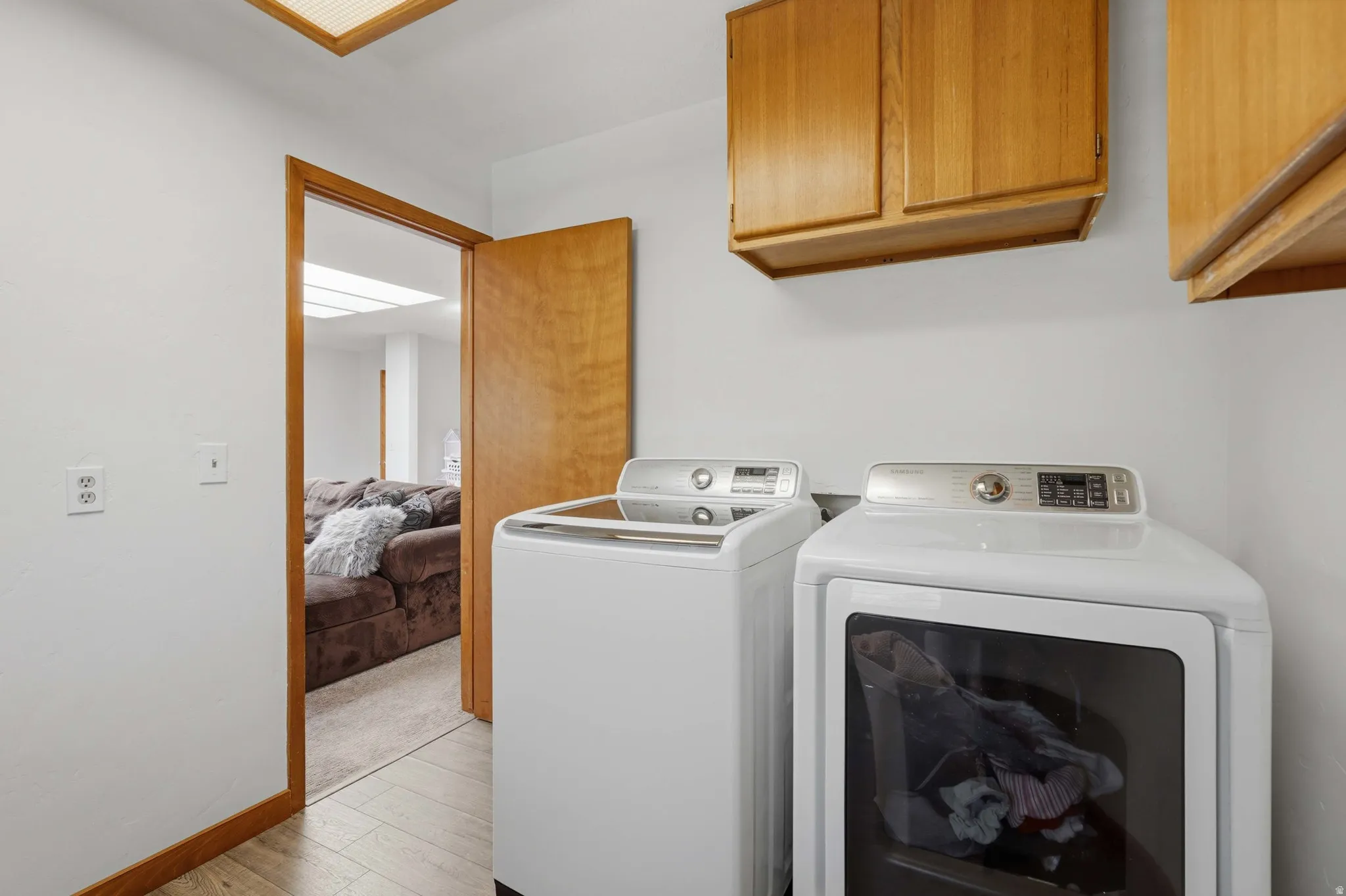 Dedicated laundry area featuring wood-finish flooring and light wood cabinetry
