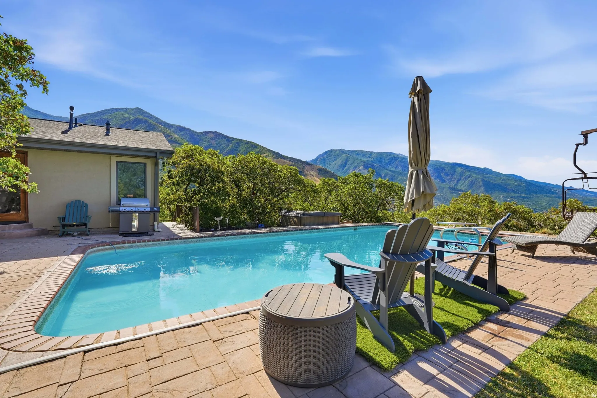 Rectangular swimming pool with surrounding paver patio and mountain scenery