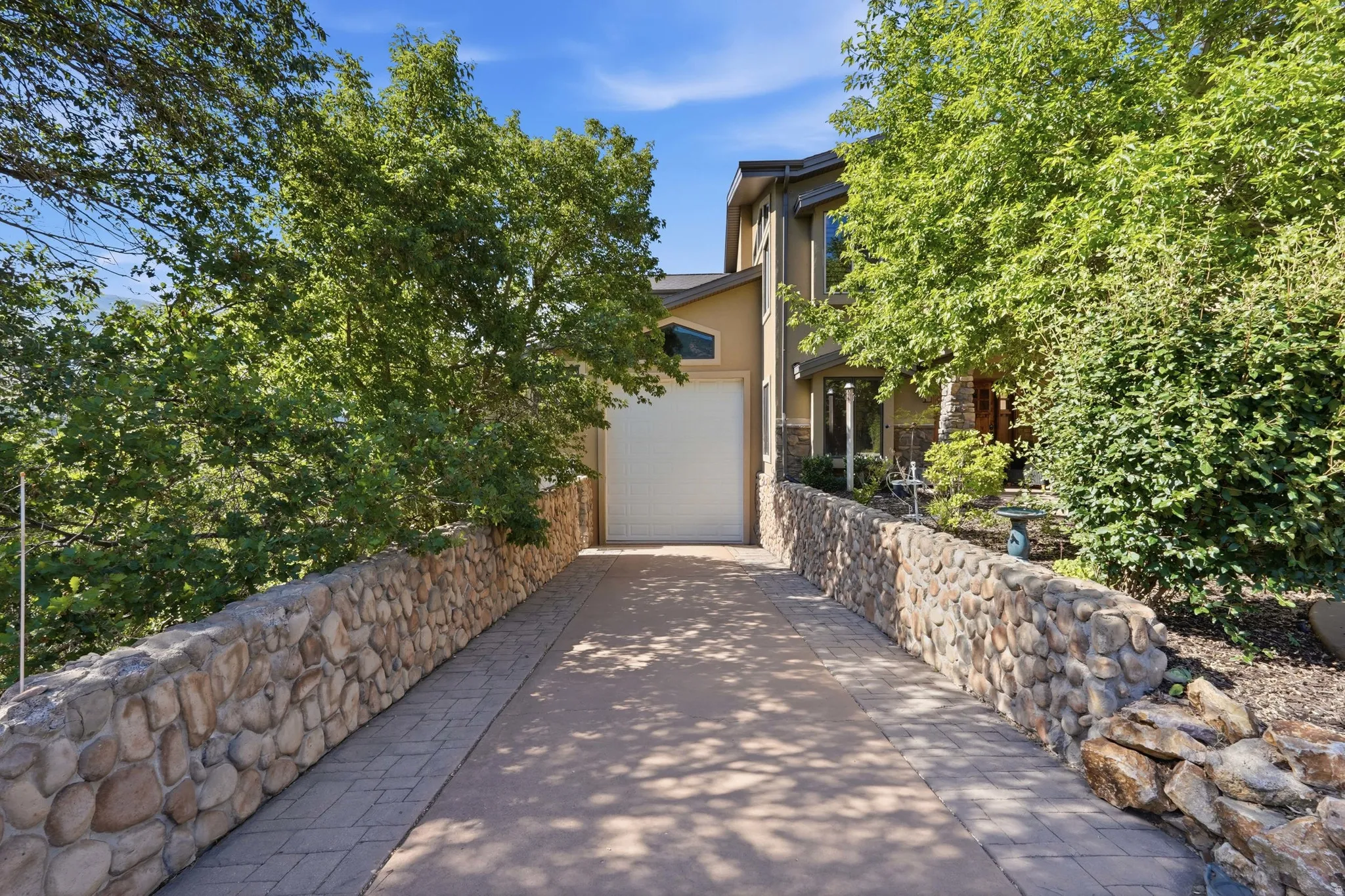 Paved driveway with stone retaining walls, leading to an attached RV garage