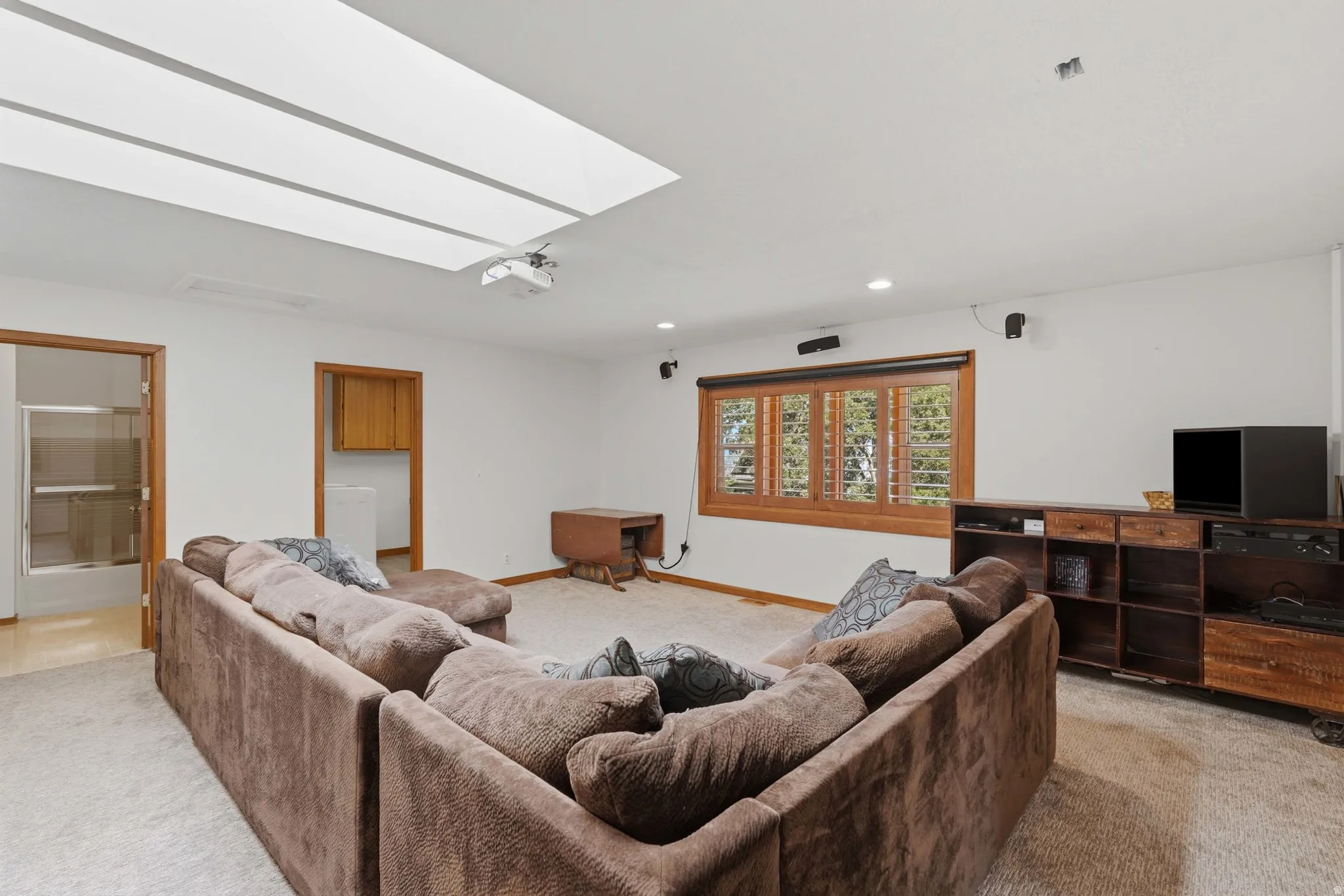 Carpeted interior space featuring a large skylight and a recessed projector