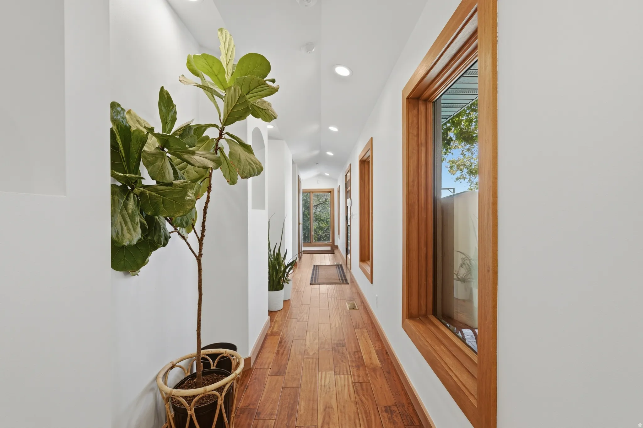 Hallway leading from the kitchen to the pool rooms,  featuring wood-finish flooring, recessed lighting, and natural wood-framed windows