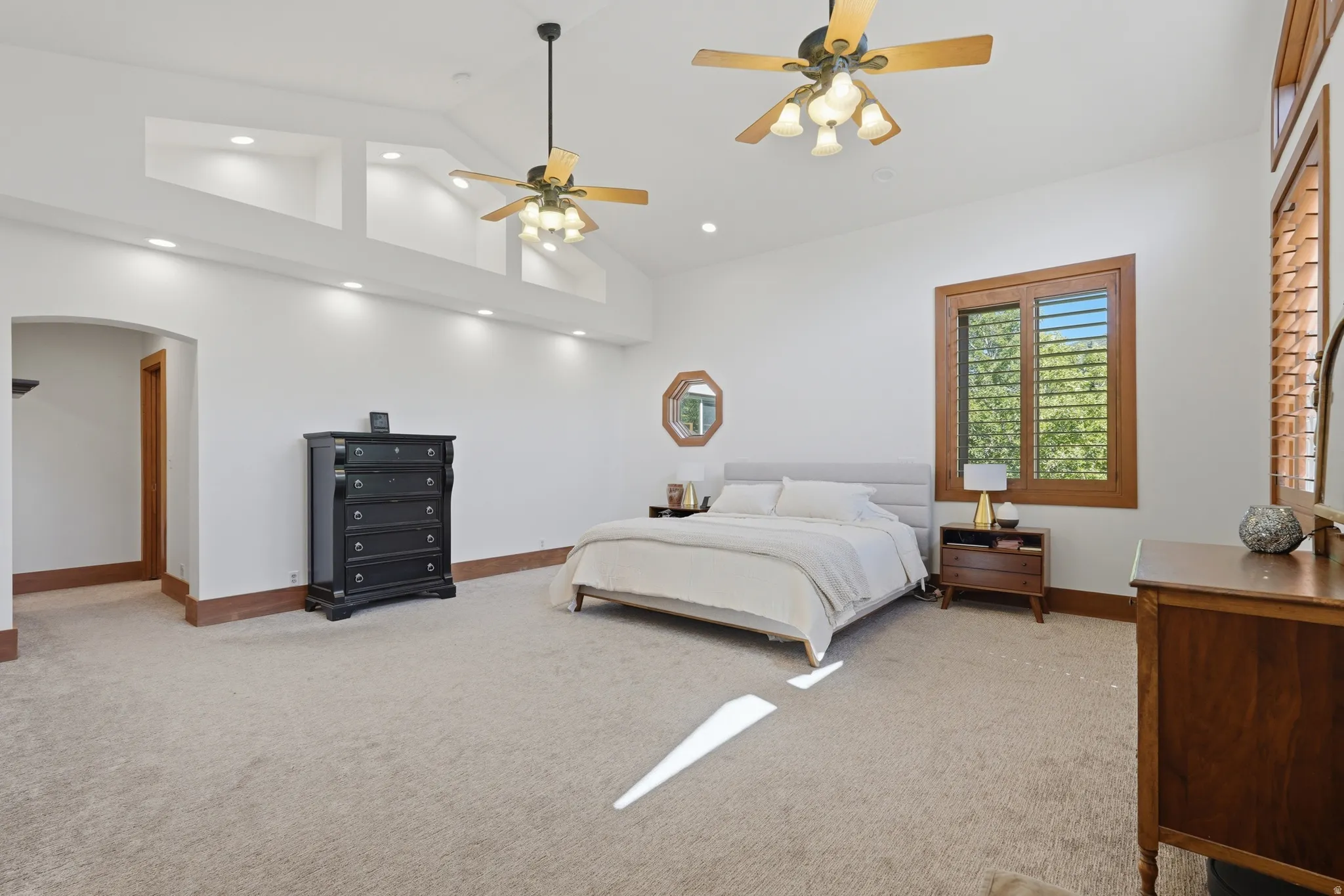 Spacious room featuring vaulted ceilings, recessed lighting, and twin ceiling fans