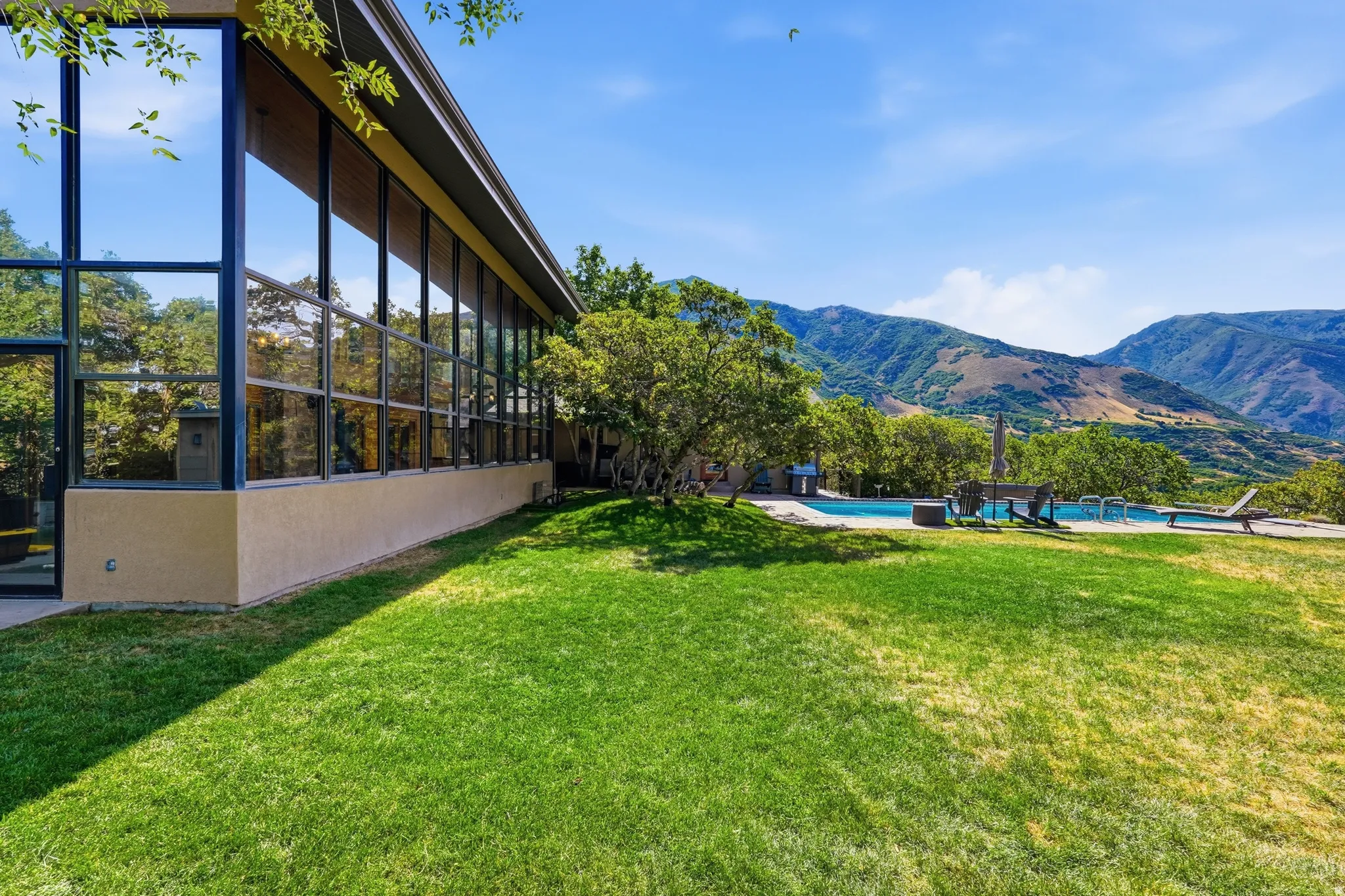 Expansive green lawn bordering a stucco-finished exterior with floor-to-ceiling windows