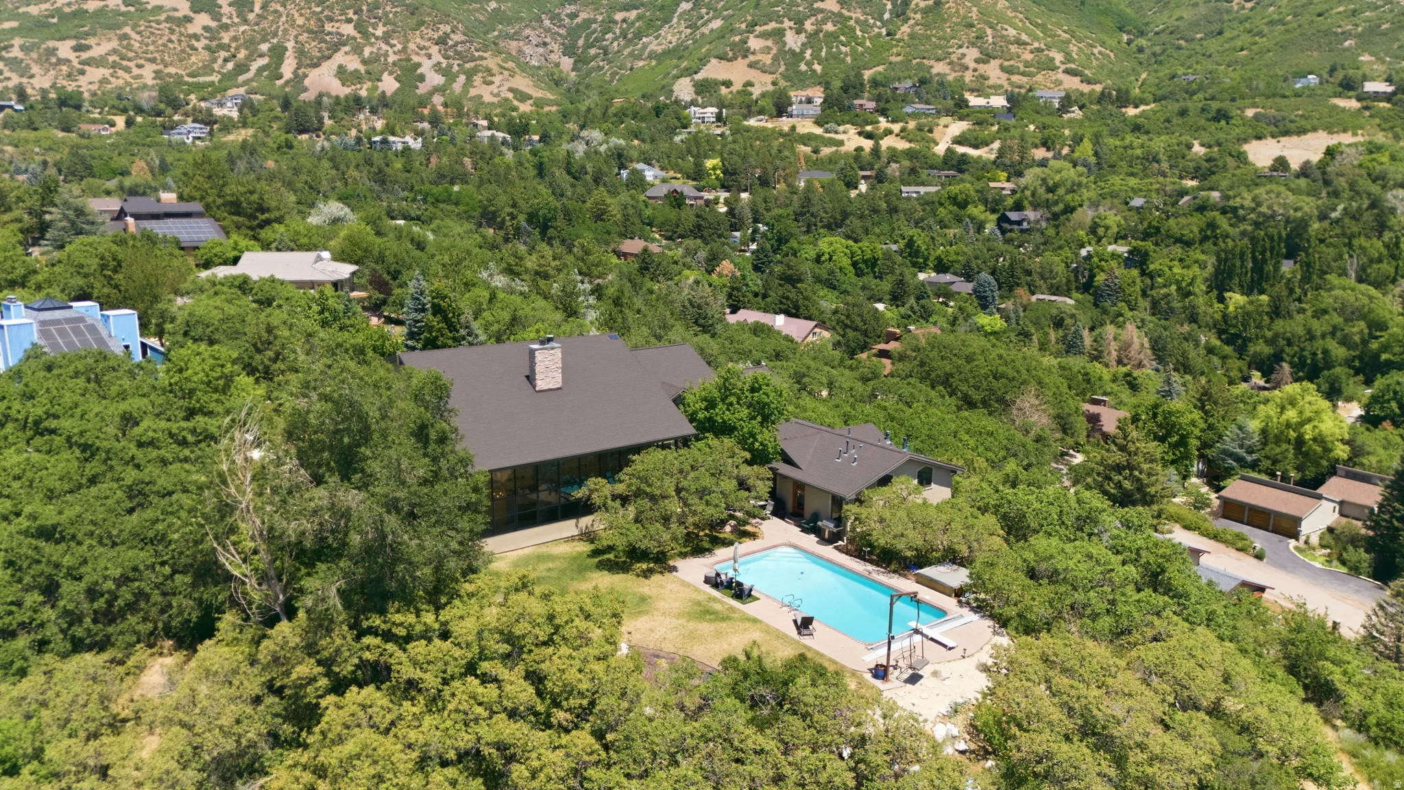 Expansive outdoor swimming pool with surrounding patio space, framed by mature trees