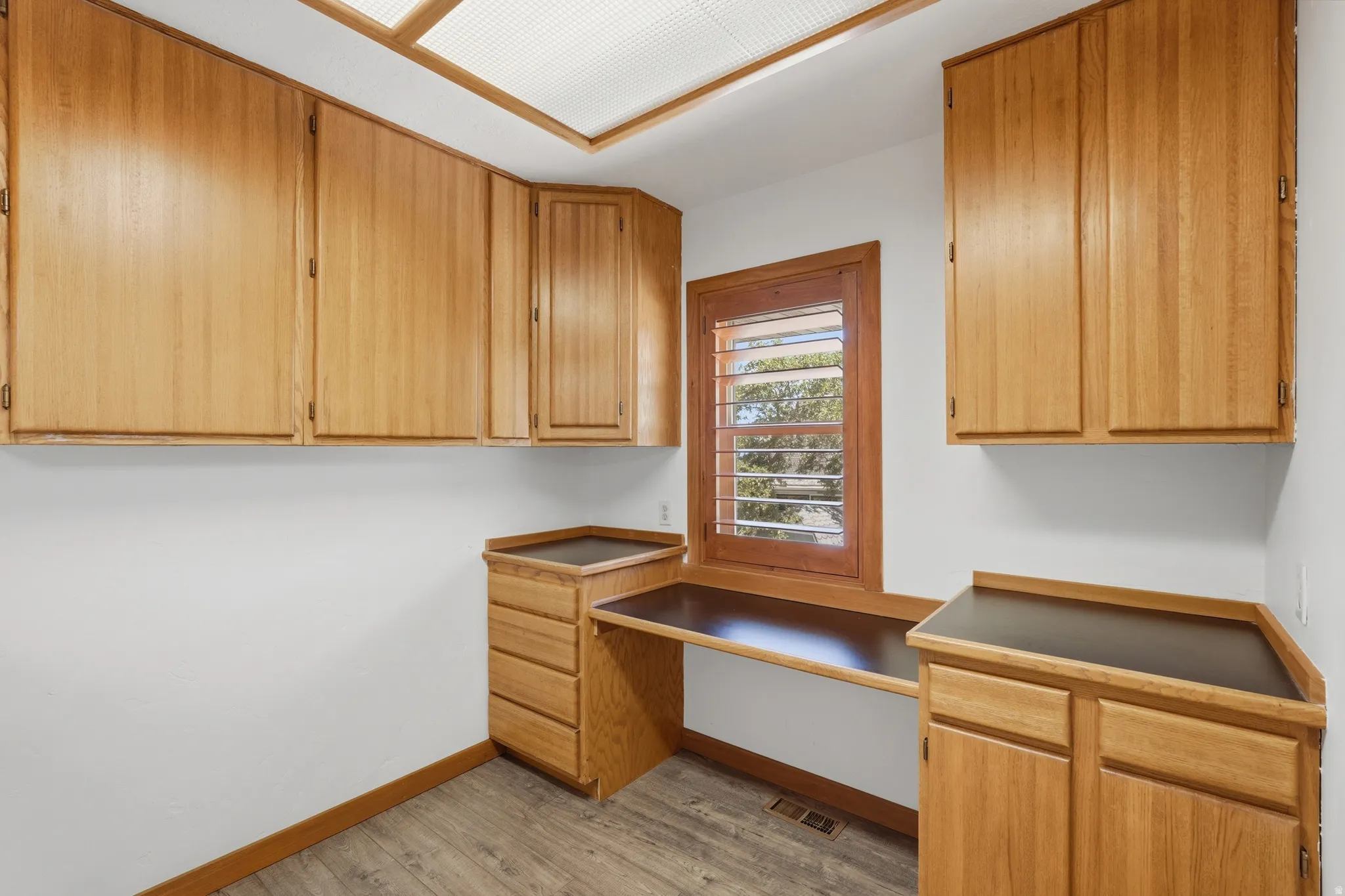 Built-in wood-finish cabinetry, integrated desk space, and window with plantation shutters