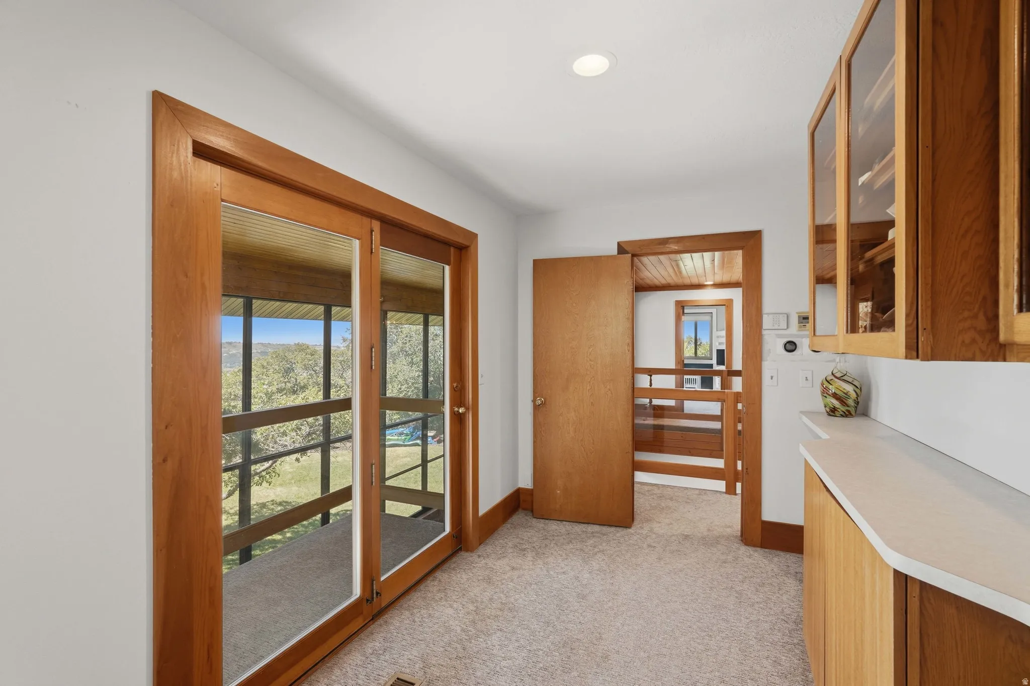Entrance into the primary. Wood-framed glass doors open to the sunroom, showcasing the yard and pool.