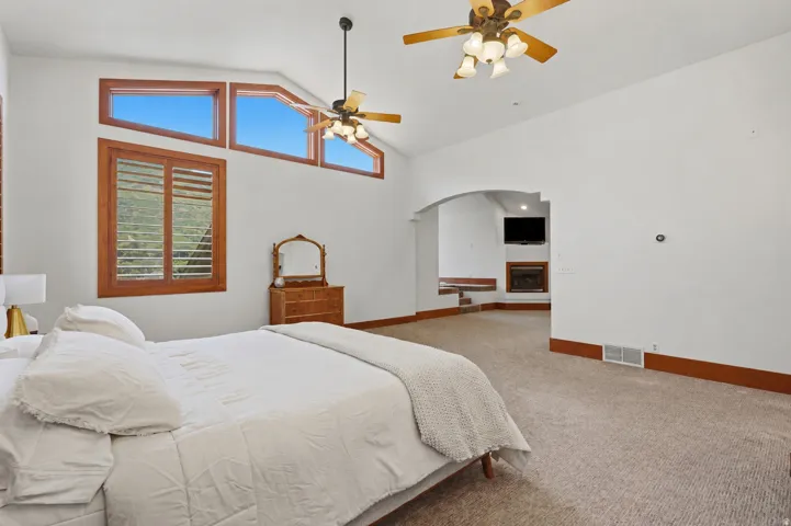 Carpeted interior space featuring a vaulted ceiling with multiple ceiling fans