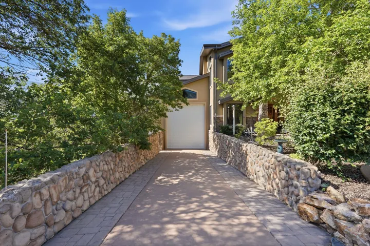 Paved driveway with stone retaining walls, leading to an attached RV garage