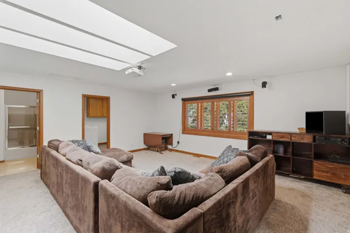 Carpeted interior space featuring a large skylight and a recessed projector