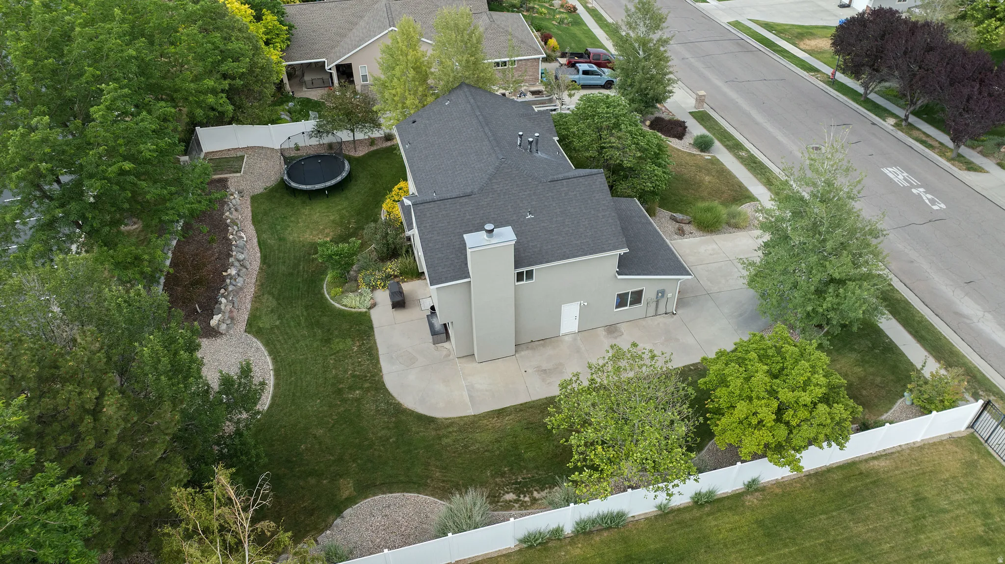 Expansive backyard featuring a manicured lawn, established landscaping, and a concrete patio