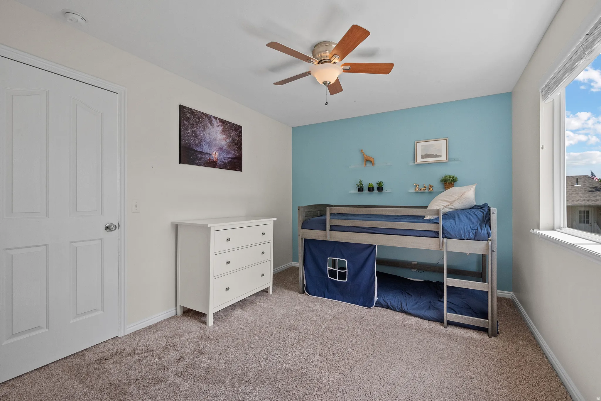 Carpeted room featuring a light blue accent wall and crisp white trim