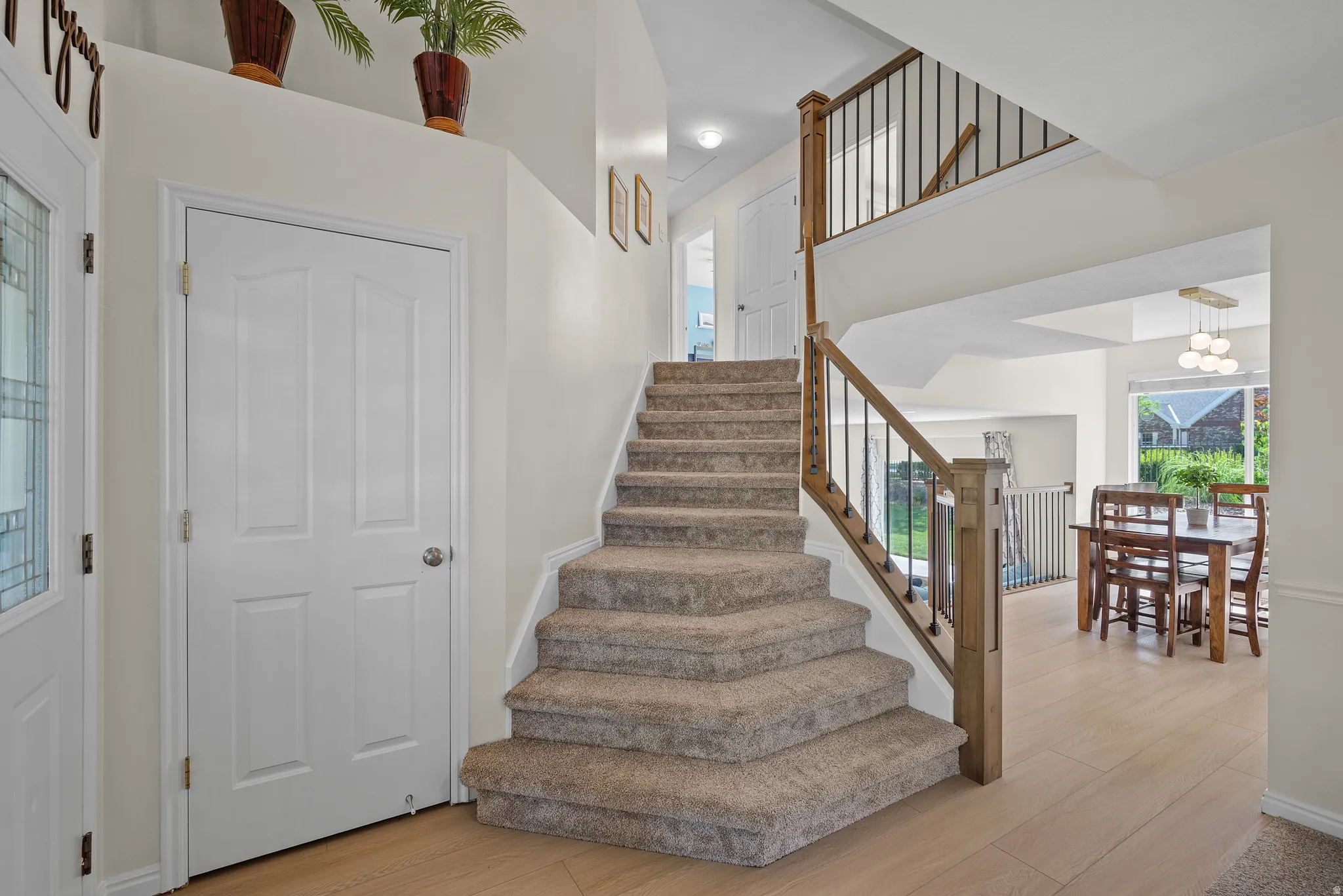 Carpeted staircase with wood-finish handrail and black iron balusters